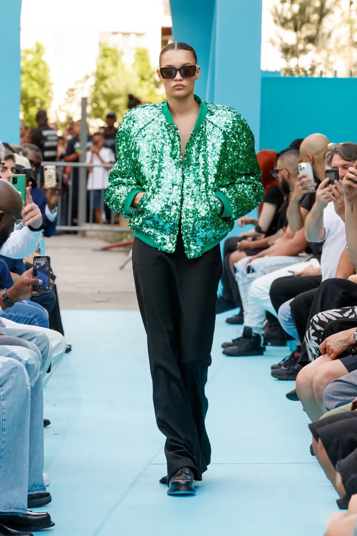 Look 24: Chiếc áo khoác bomber đính sequin màu xanh lá cây đầy nổi bật, đi kèm là quần tây đen và giày Oxford.